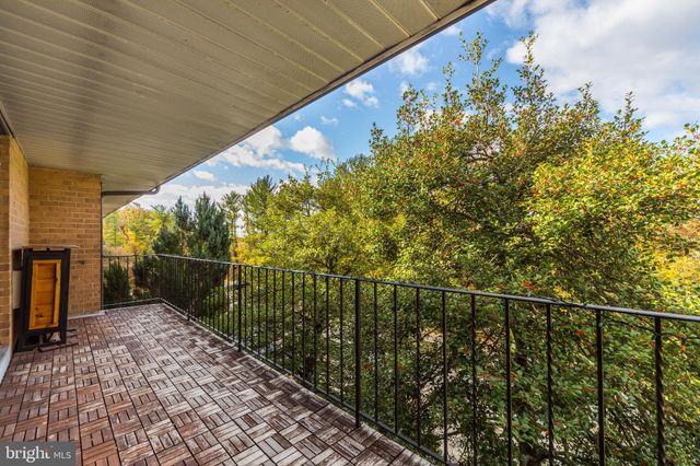 a view of a hallway with wooden floor and a bathroom