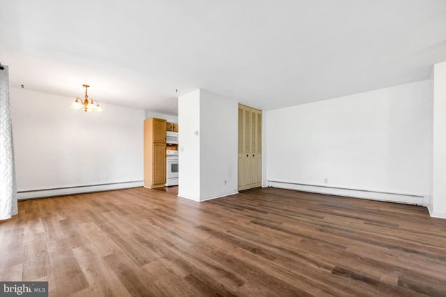 a view of an empty room with wooden floor closet and a window
