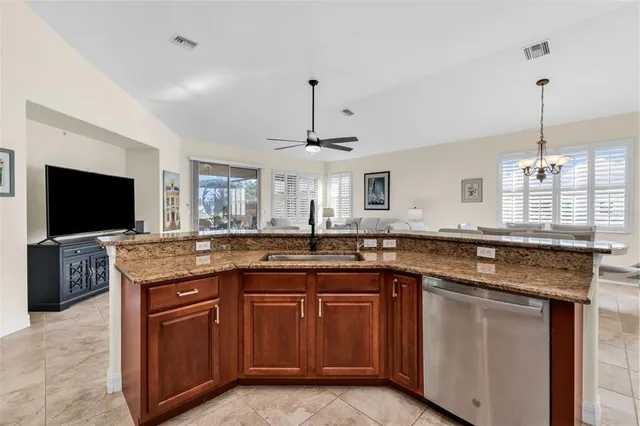 a kitchen with stainless steel appliances kitchen island granite countertop a dining table chairs and a refrigerator