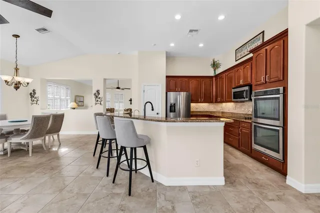 a kitchen with stainless steel appliances a refrigerator a stove a sink dishwasher with a dining table and chairs