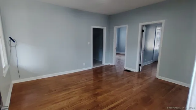 a view of an empty room with wooden floor and closet