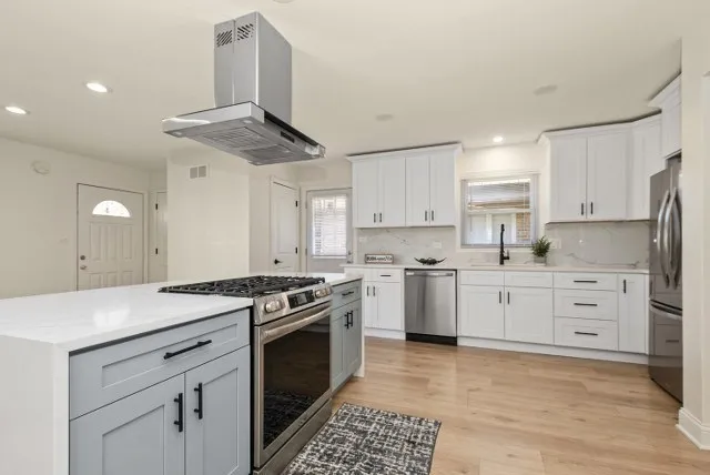 a kitchen with stainless steel appliances a stove a sink and white cabinets