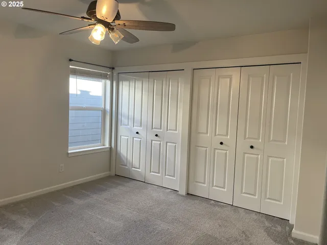 an empty room with windows and fan