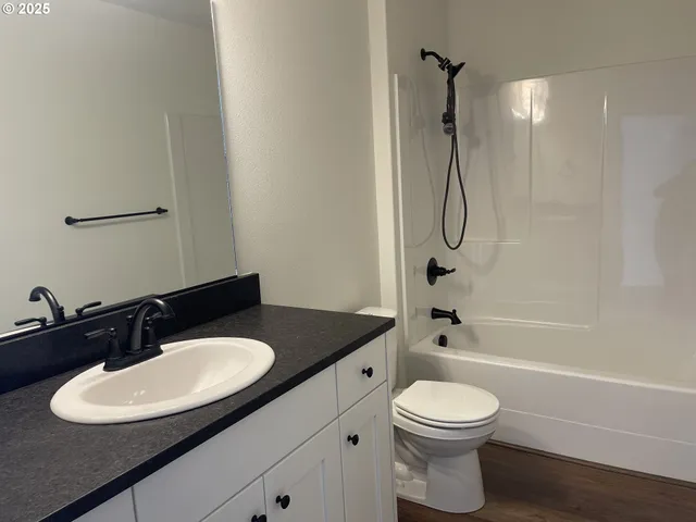 a bathroom with a granite countertop sink toilet a mirror and shower