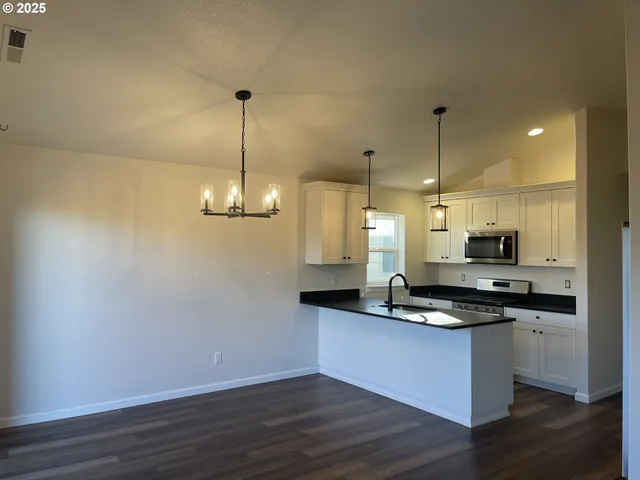 a kitchen with kitchen island granite countertop a sink a counter space appliances and cabinets