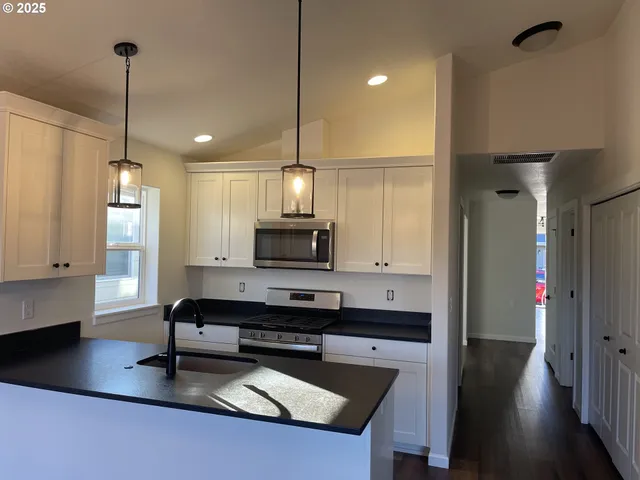 a kitchen with stainless steel appliances a stove a sink a microwave a refrigerator and cabinets