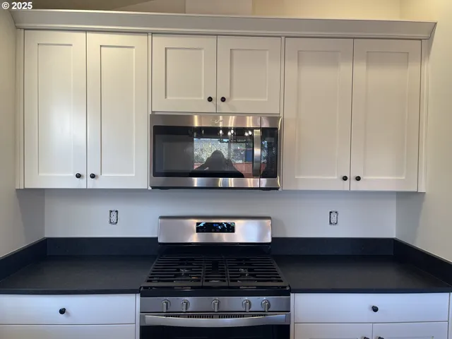 a kitchen with stainless steel appliances granite countertop white cabinets and black stove top oven with granite countertops