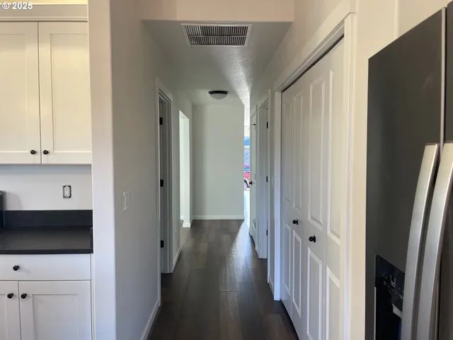 a view of a hallway with wooden floor and cabinets