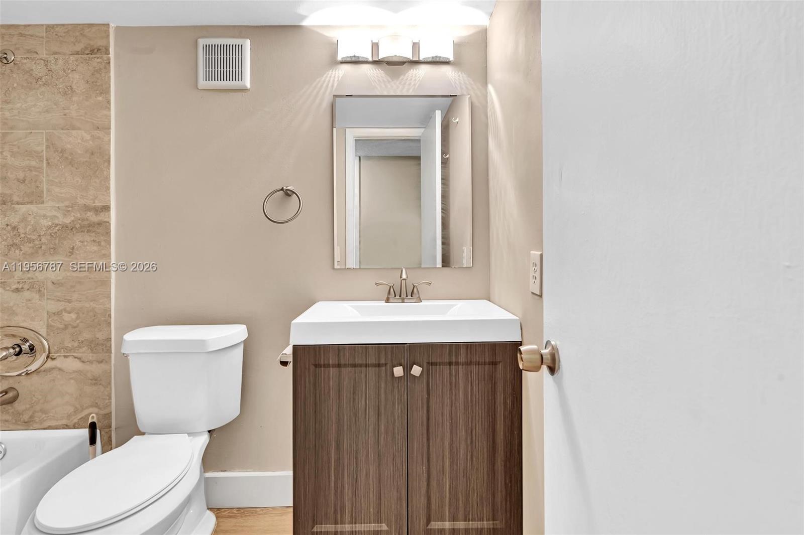 400 Commodore Drive, Unit 215 Plantation, FL 33325 - Photo 29 of 30 a bathroom with a granite countertop toilet a sink and mirror