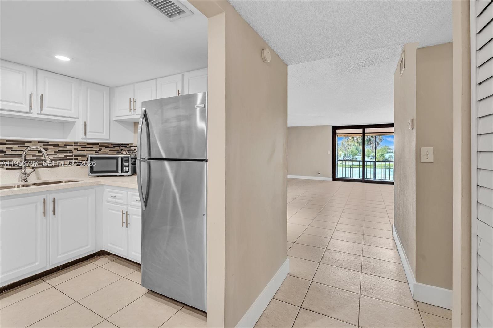 400 Commodore Drive, Unit 215 Plantation, FL 33325 - Photo 7 of 30 a kitchen with white cabinets and refrigerator