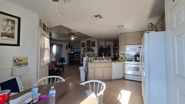 a kitchen with stainless steel appliances granite countertop a refrigerator a stove a sink dishwasher and white cabinets with wooden floor