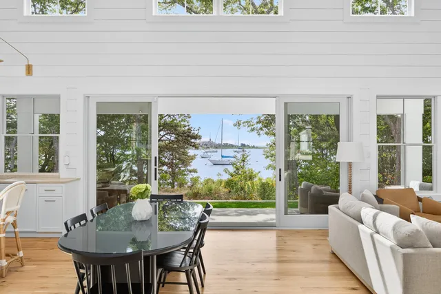 a kitchen with stainless steel appliances granite countertop a stove a sink dishwasher and a dining table with wooden floor