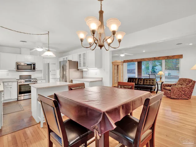 a dining room with wooden floor a chandelier a wooden table and chairs
