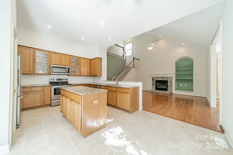 a large kitchen with stainless steel appliances kitchen island granite countertop a stove a sink a refrigerator and a granite counter tops with white cabinets