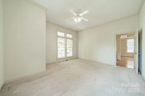an empty room with windows and chandelier fan