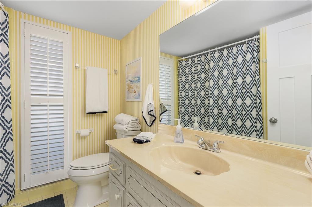 237 Palm Drive, Unit 1 Naples, FL 34112 - Photo 18 of 30 a bathroom with a sink a toilet and shower curtain