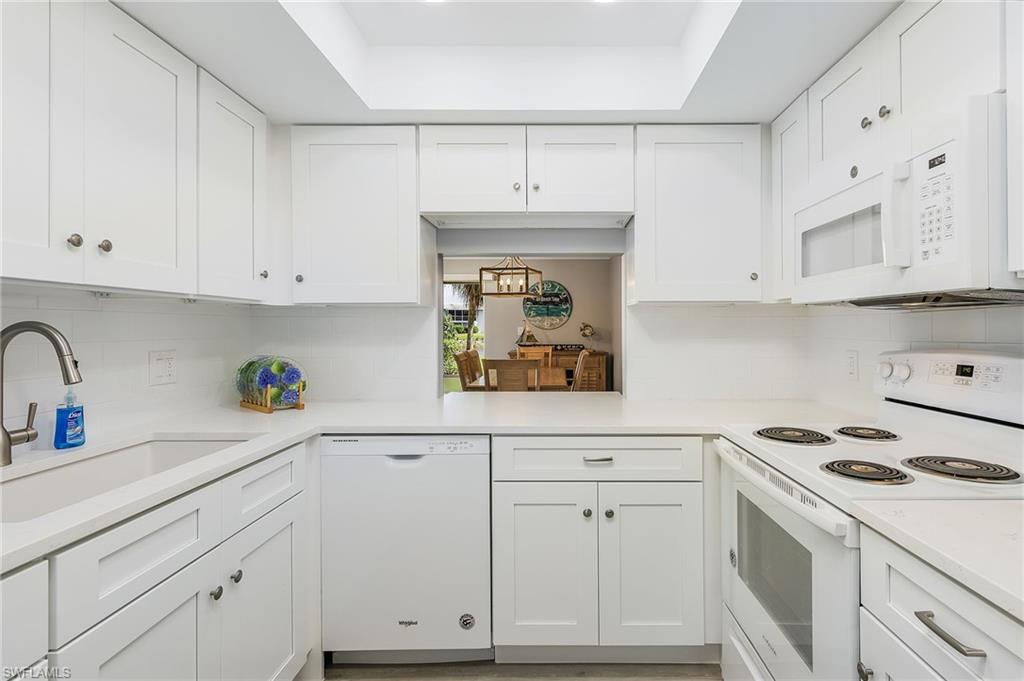237 Palm Drive, Unit 1 Naples, FL 34112 - Photo 9 of 30 a kitchen with white cabinets and white appliances