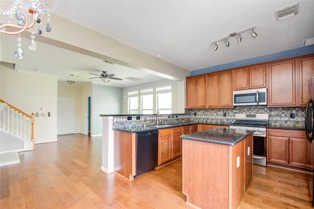 a kitchen with stainless steel appliances granite countertop a stove a sink dishwasher and a refrigerator