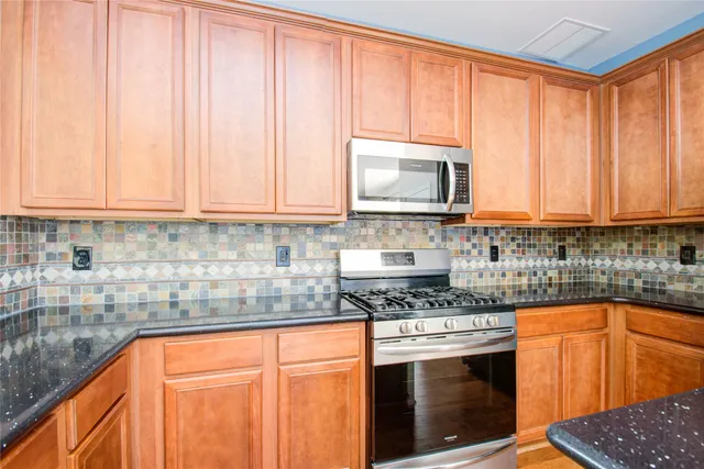 a kitchen with stainless steel appliances granite countertop a stove a sink and a microwave