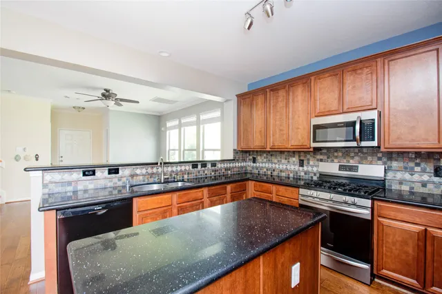 a kitchen with stainless steel appliances granite countertop sink stove top oven and microwave