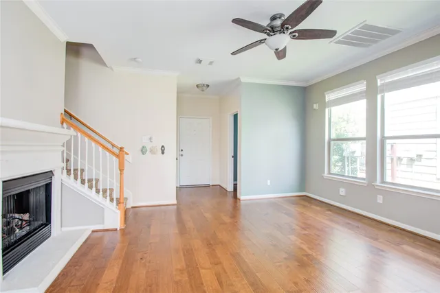 a view of an empty room with chandelier fan and wooden floor