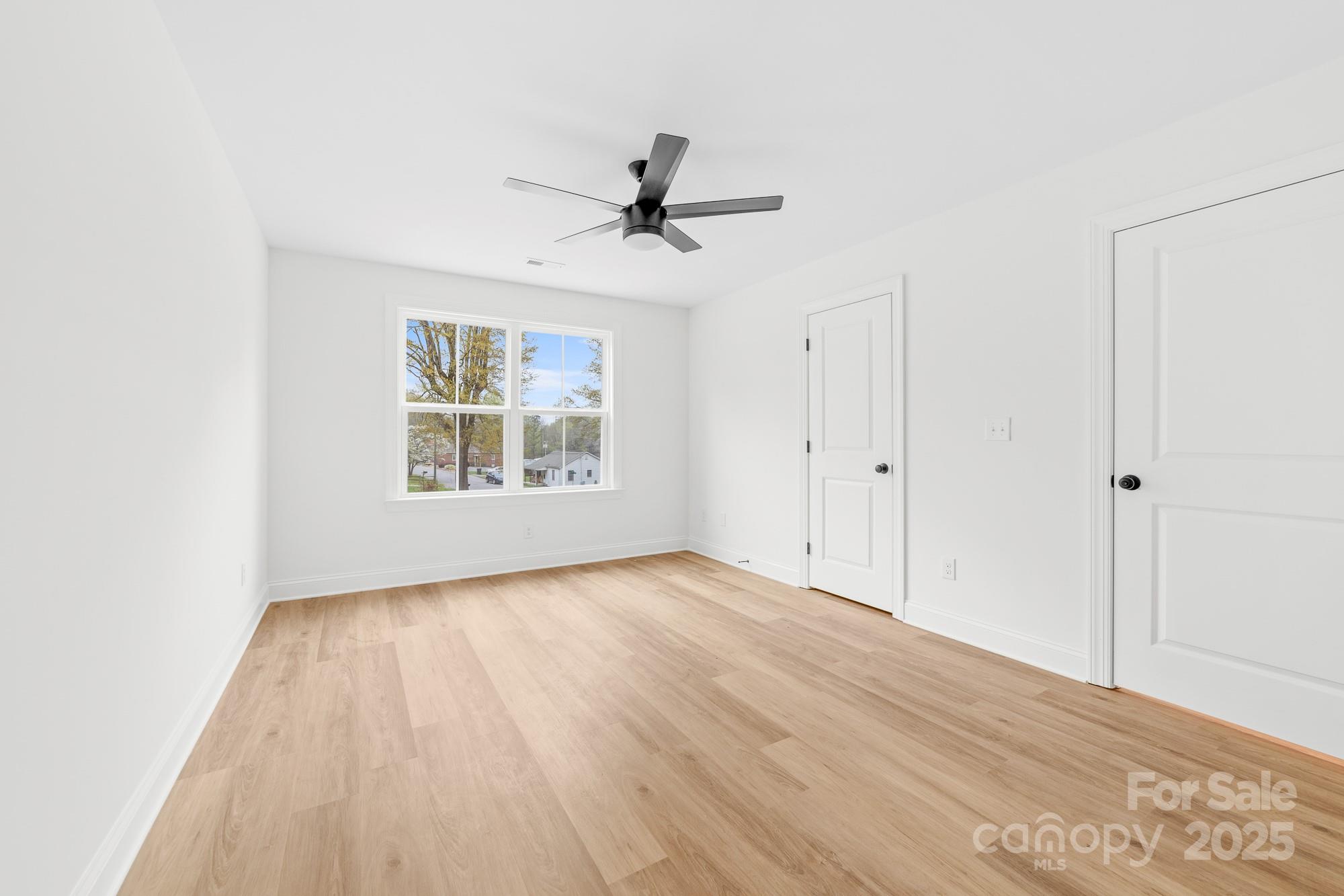 103 West Irwin Street Cherryville, NC 28021 - Photo 20 of 30 an empty room with wooden floor chandelier fan and windows