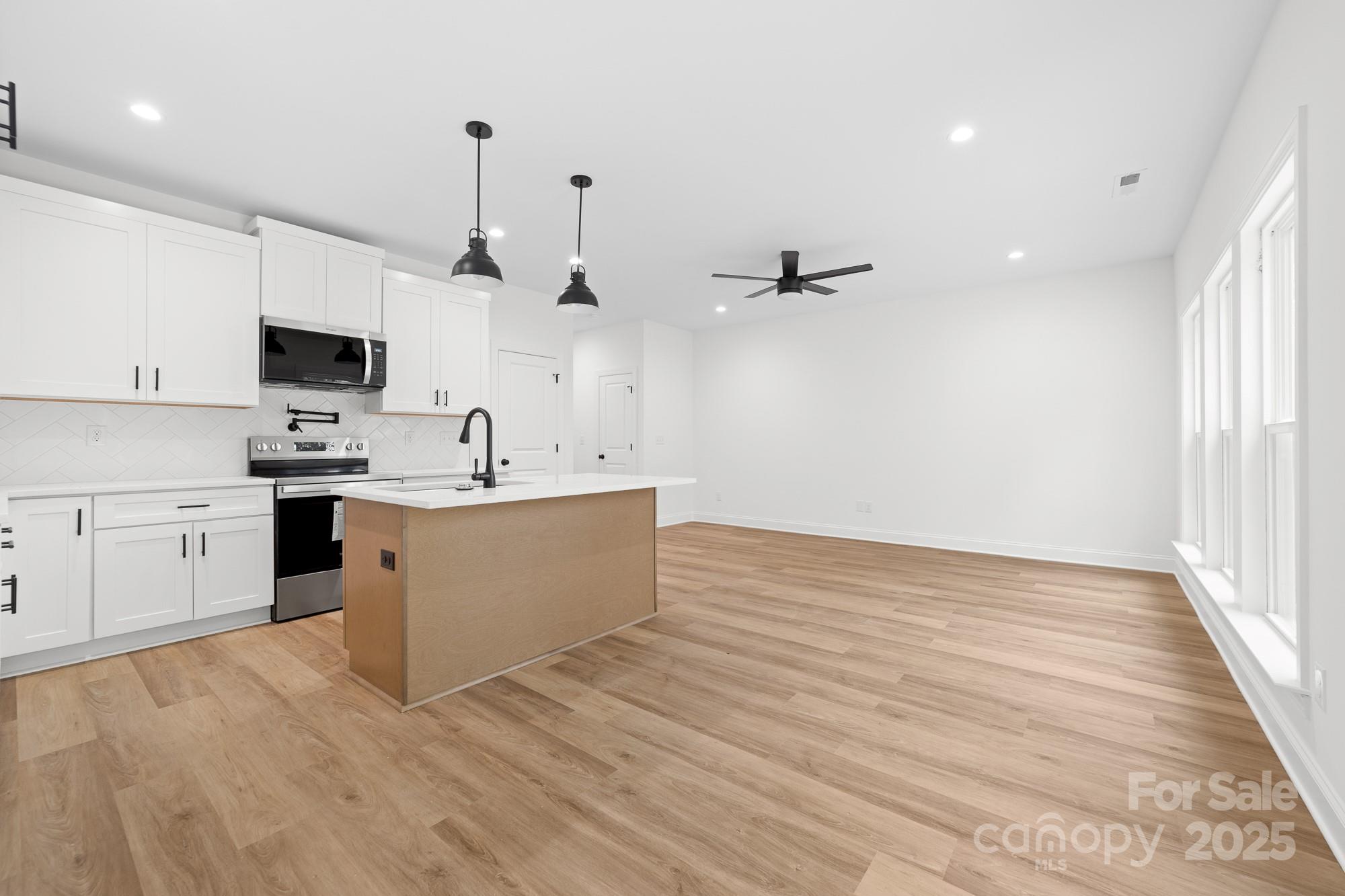 103 West Irwin Street Cherryville, NC 28021 - Photo 9 of 30 a view of a kitchen with kitchen island a sink dishwasher and a stove with wooden floor