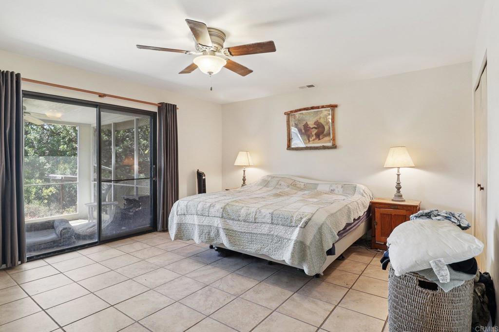 23833 Gymkhana Road Ramona, CA 92065 - Photo 15 of 29 a spacious bedroom with a bed painting on wall and a large window