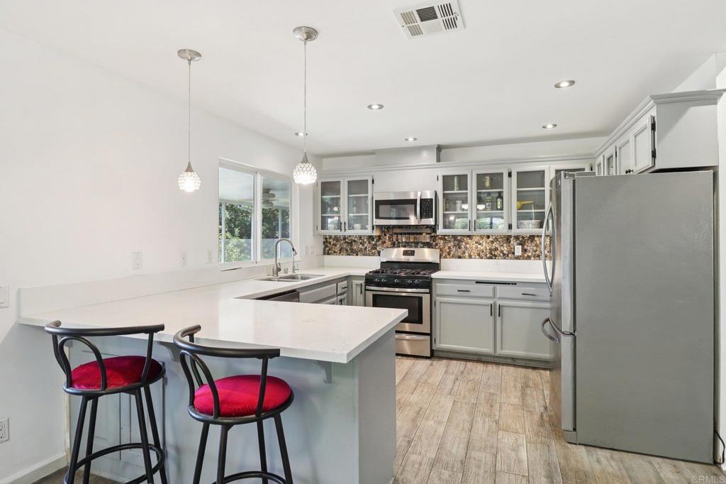 23833 Gymkhana Road Ramona, CA 92065 - Photo 9 of 29 a kitchen with stainless steel appliances kitchen island granite countertop a refrigerator a stove top oven a sink dishwasher and a dining table with wooden floor