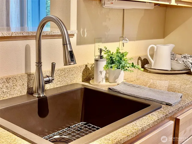 a kitchen with stainless steel appliances granite countertop a stove a sink and a refrigerator with wooden floors