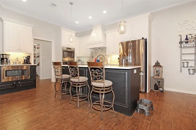 a kitchen with stainless steel appliances a dining table chairs refrigerator and sink