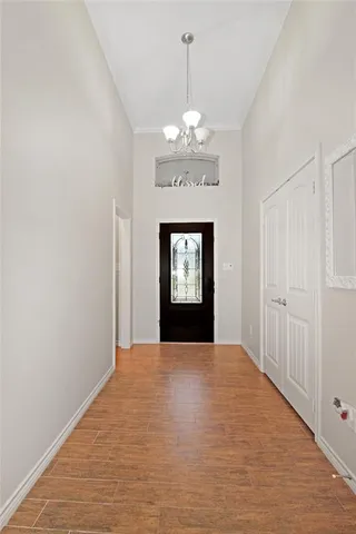 a view of an empty room with window and chandelier fan