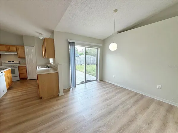 a view of a kitchen and an empty room with wooden floor and a window