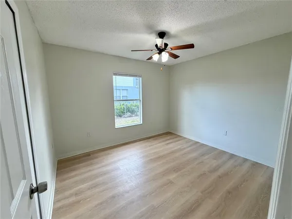 an empty room with wooden floor fan and windows