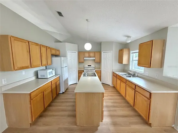 a large kitchen with stainless steel appliances a sink dishwasher a stove and a large window