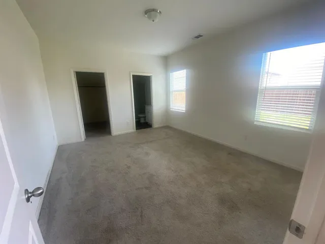 a kitchen with stainless steel appliances granite countertop a refrigerator a stove a sink and white cabinets with wooden floor