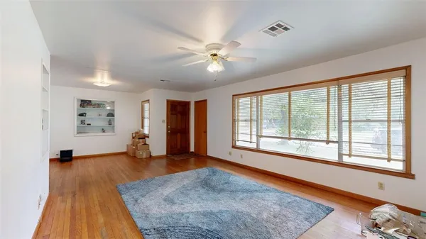 a view of an empty room with a window and wooden floor