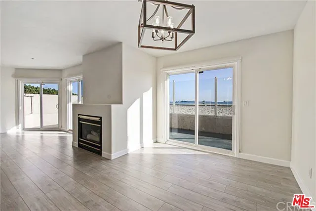 an empty room with wooden floor fireplace and windows