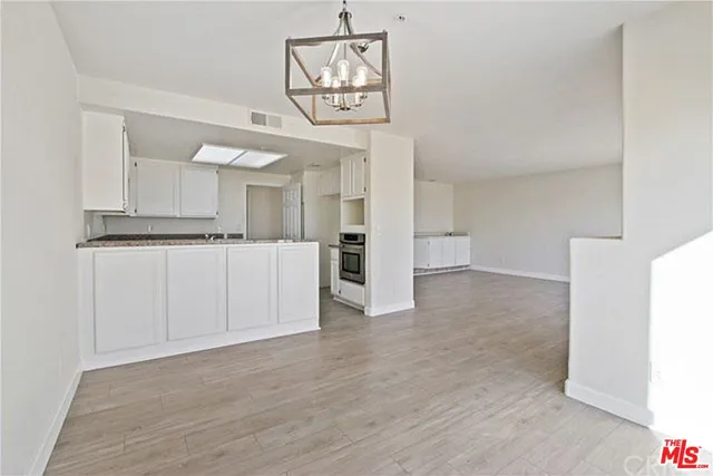 a view of a hallway with wooden floor and a kitchen