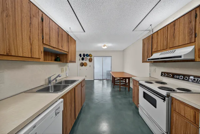 a kitchen with stainless steel appliances granite countertop a sink a stove and a wooden cabinets