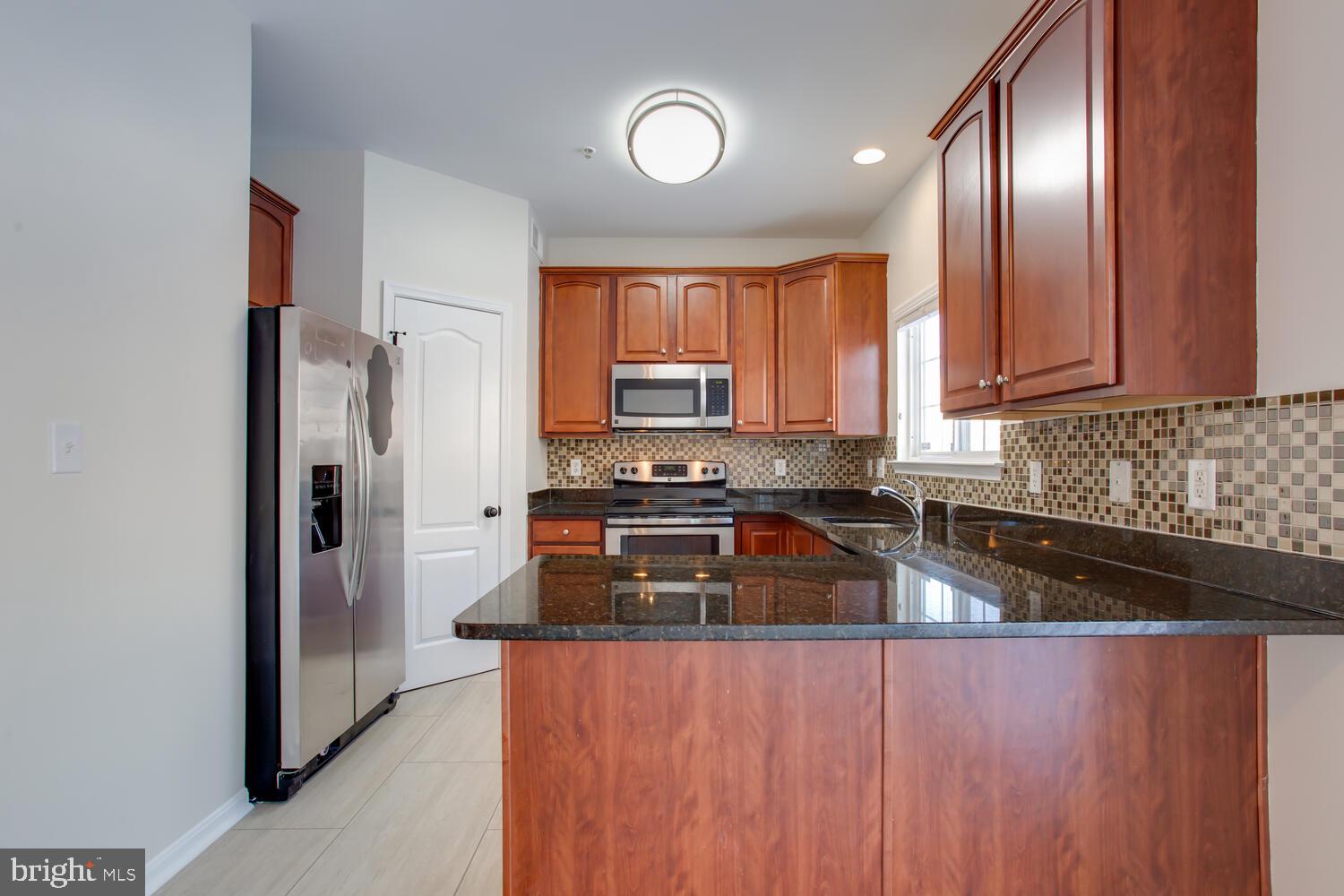 7024 Commander Howe Terrace Brandywine, MD 20613 - Photo 11 of 34 a kitchen with granite countertop stainless steel appliances a refrigerator a stove a sink and a microwave