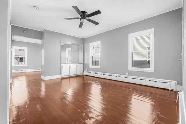 a view of an empty room with window and wooden floor