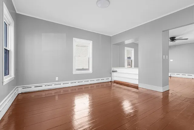 an empty room with wooden floor and windows