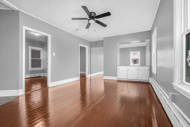 a view of an empty room with window and wooden floor