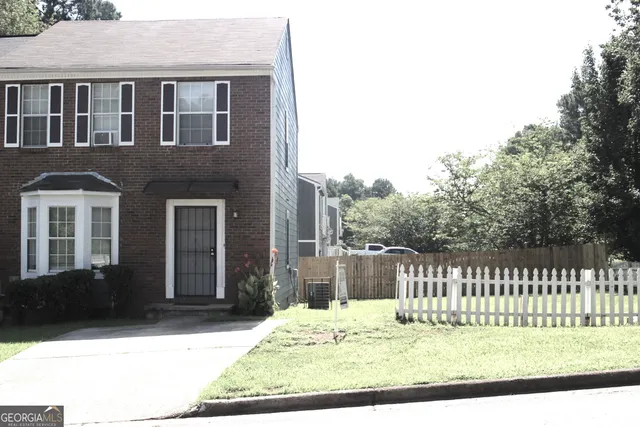 a view of a house with a small yard and wooden fence