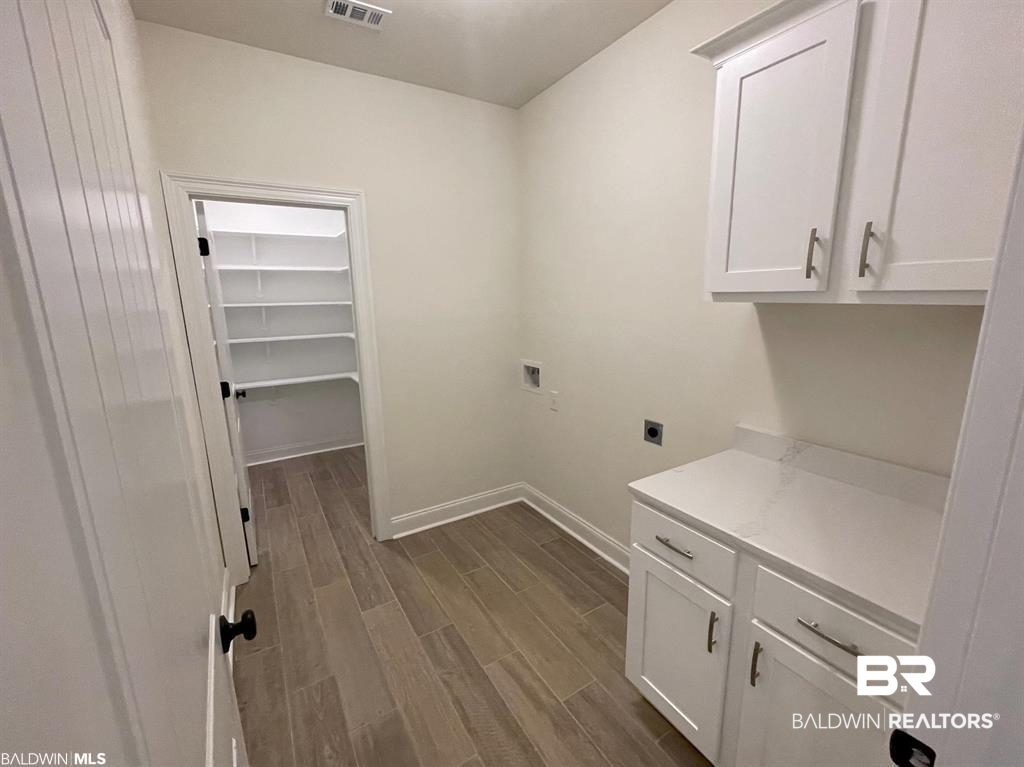22258 Hibiscus Circle Foley, AL 36535 - Photo 22 of 26 Laundry area with wood finish floors, washer hookup, baseboards, cabinet space, and electric dryer hookup