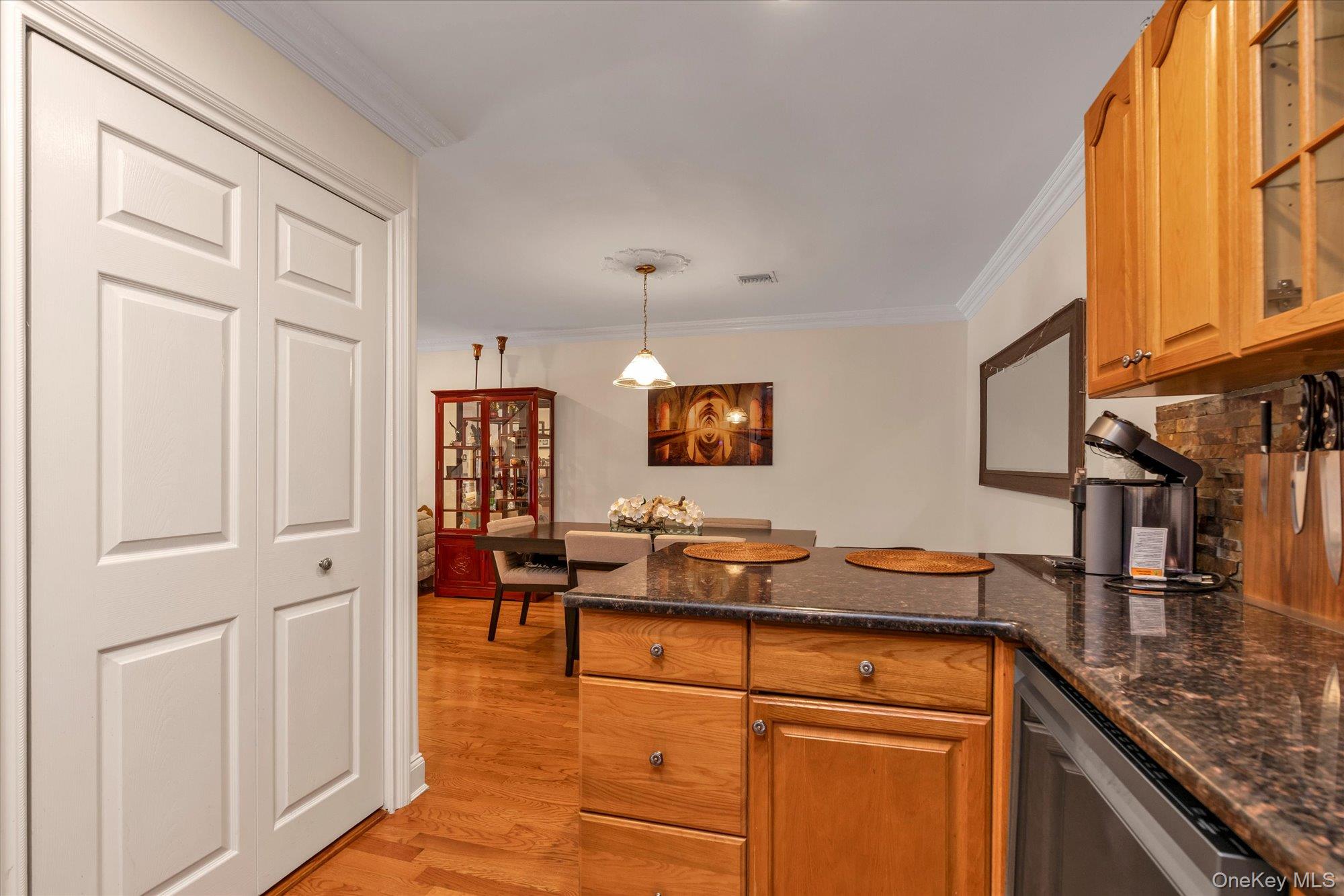 150 I U Willets Road Albertson, NY 11507 - Photo 12 of 21 Open kitchen featuring wood-finish cabinetry, dark granite countertops, and a stone tile backsplash and washer dryer area.