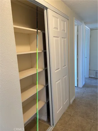 a view of an empty room with cabinet and door