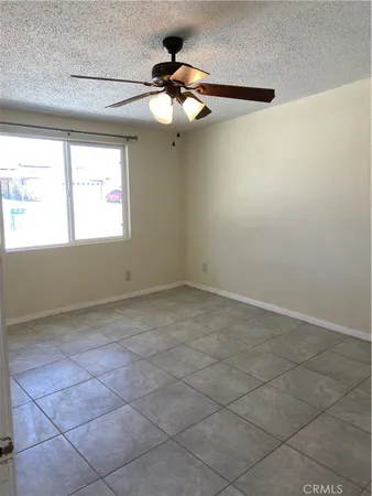 an empty room with a chandelier fan and windows
