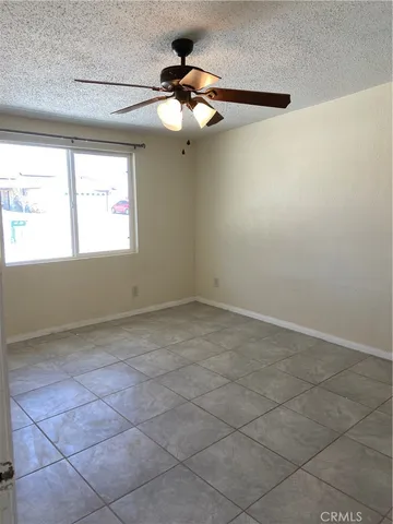 an empty room with a chandelier fan and windows